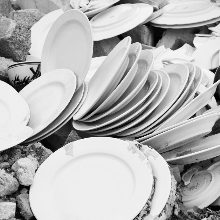 Een stapel gebroken witte borden en scherven in zwart-wit