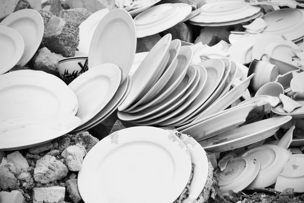Een stapel gebroken witte borden en scherven in zwart-wit